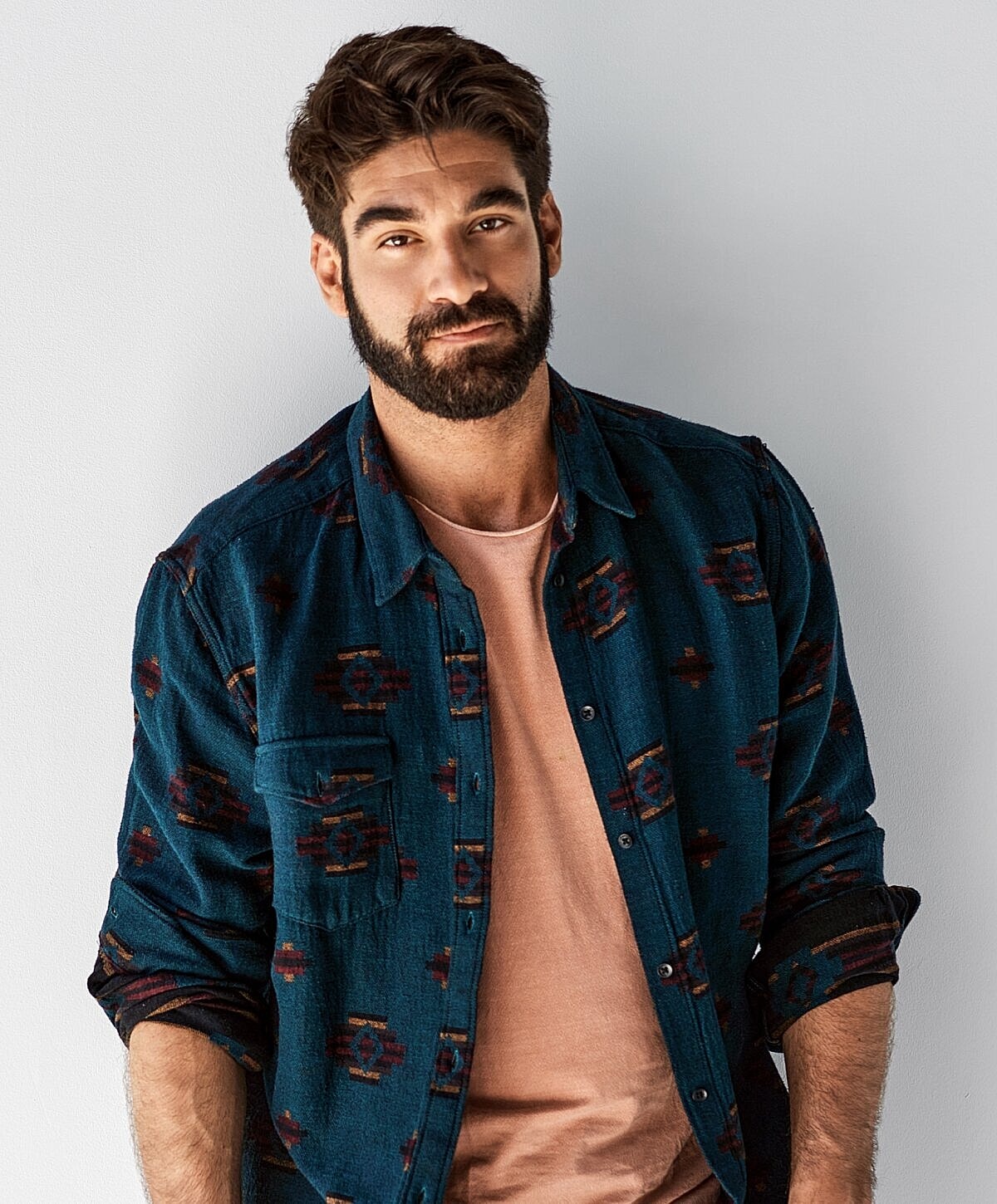 Man with beard wearing stylish patterned shirt.
