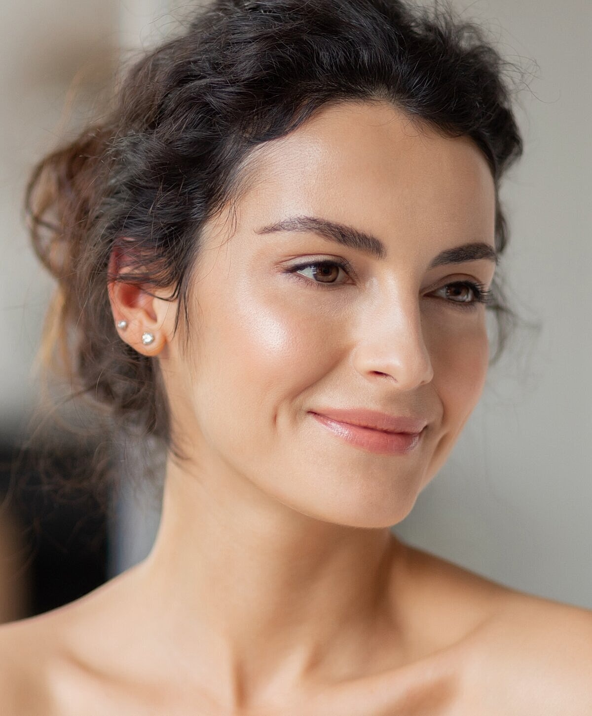 Smiling woman with curly hair and natural makeup.