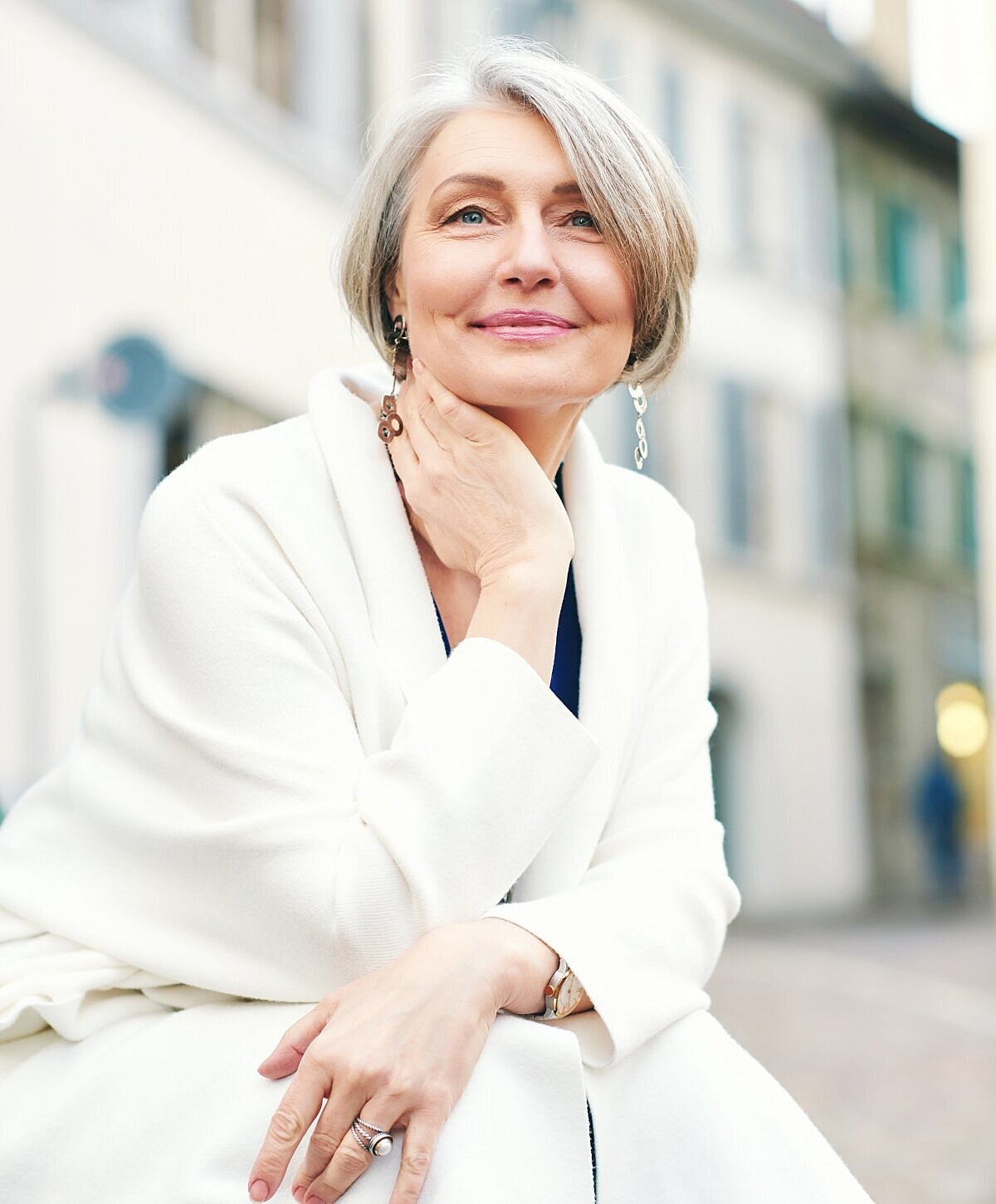 Smiling woman in white coat outdoors.