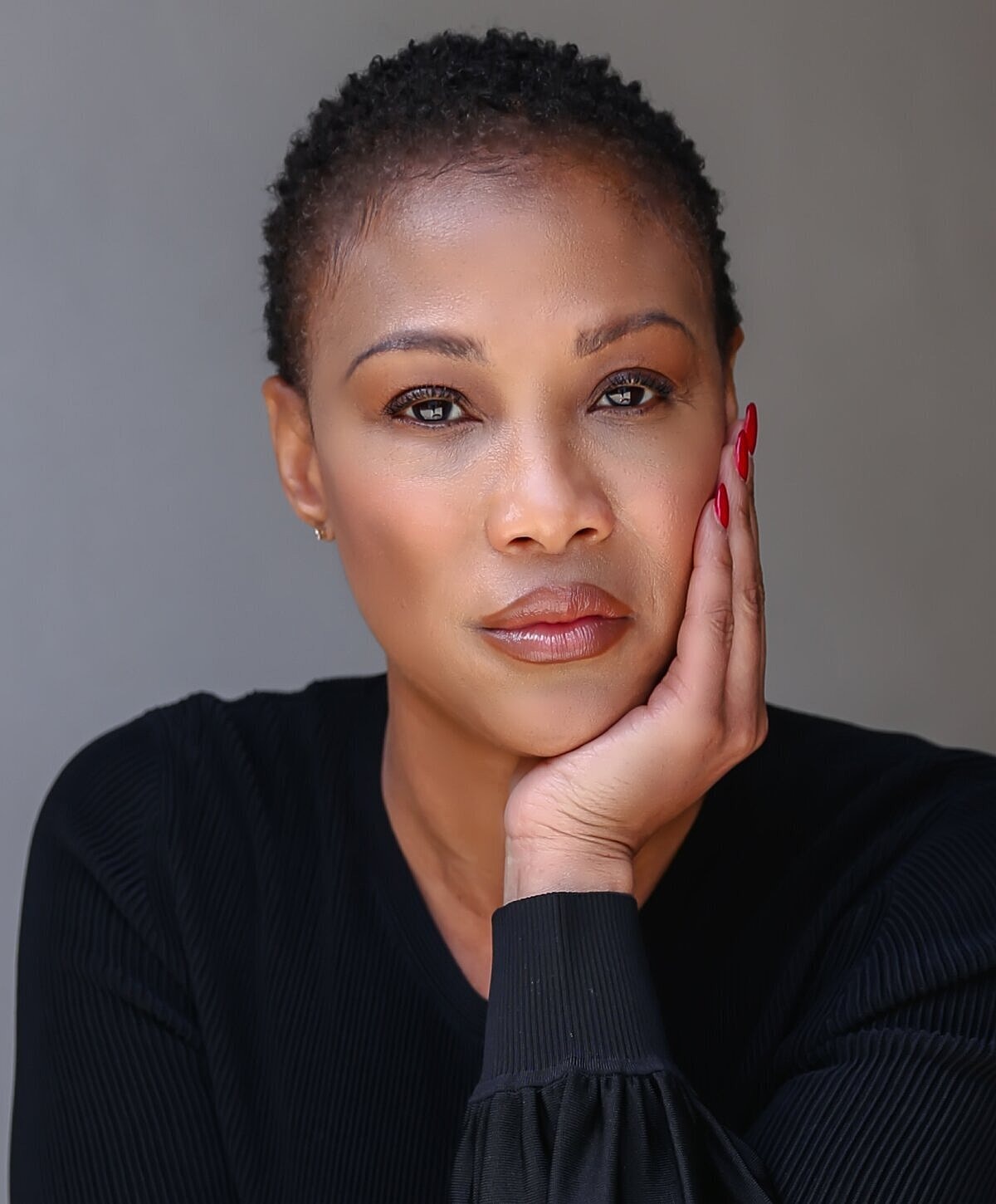 Woman with short hair resting her chin thoughtfully.